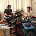Four musicians rehearse together with headphones and electronic instruments