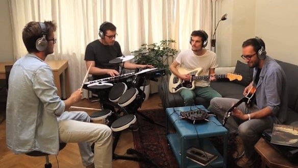 Four musicians rehearse together with headphones and electronic instruments